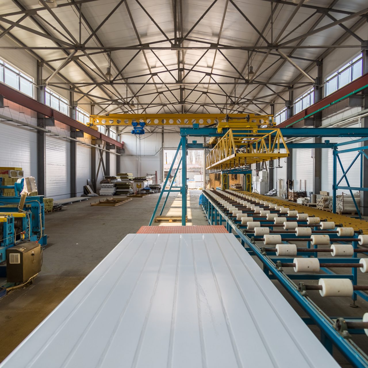 Thermal insulation sandwich panel production line. Machine tools, roller conveyor and overhead crane in workshop.